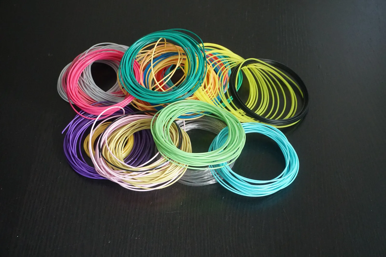 Loose coils of filament in many colours on a dark table