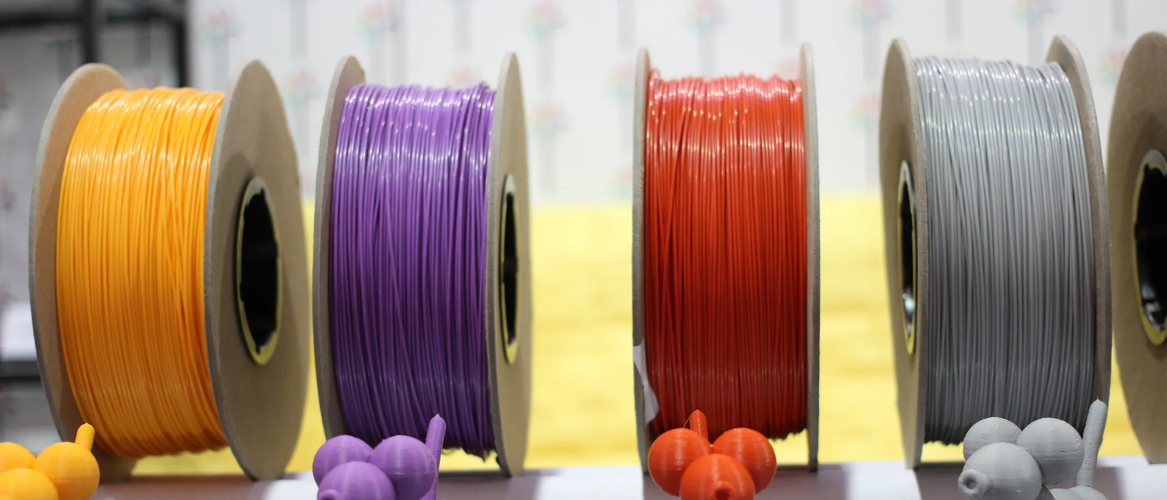 Spools of orange, purple, red and grey filament on a shelf above printed figurines